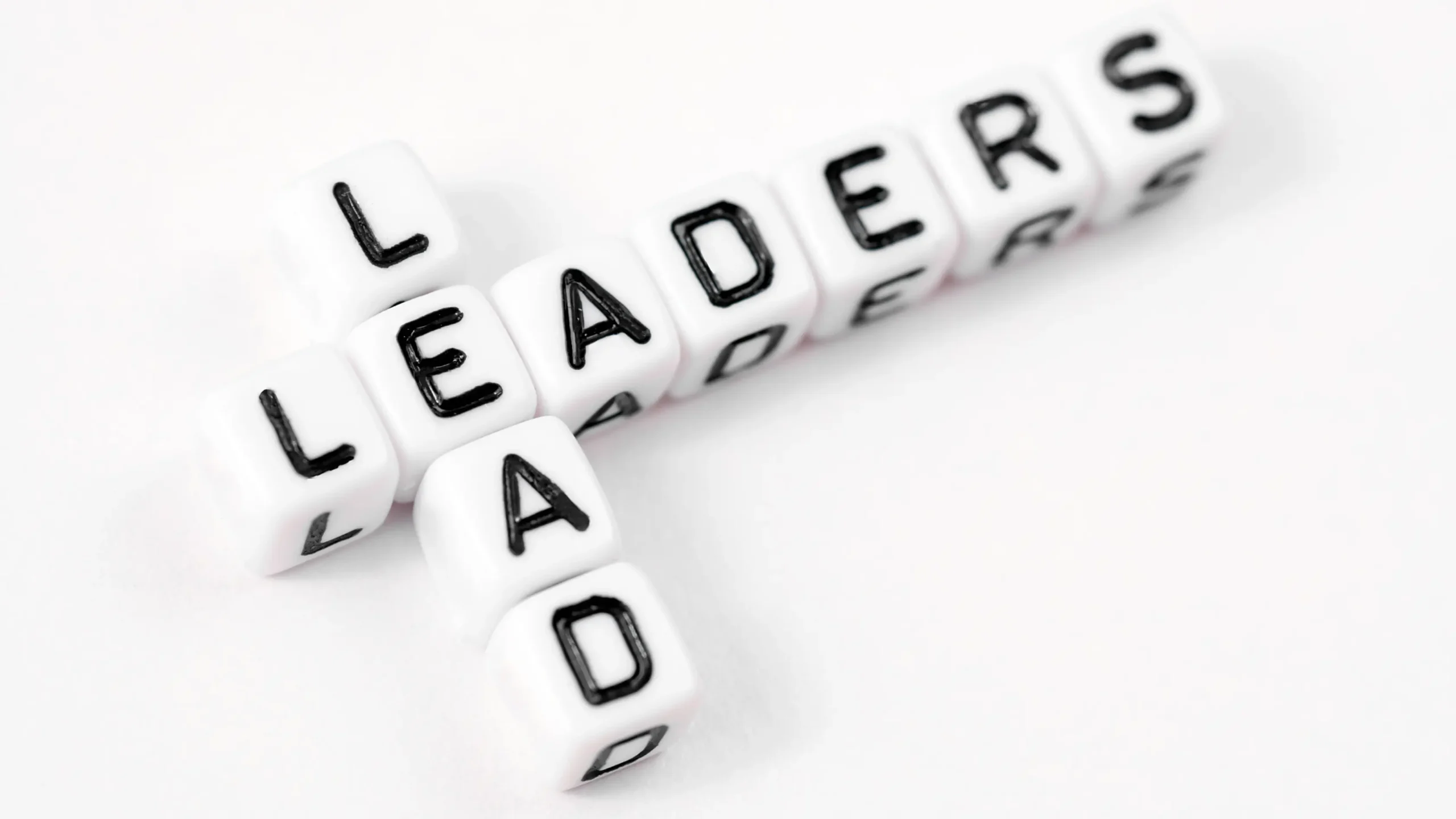 White tiles with black letters read Leaders Lead